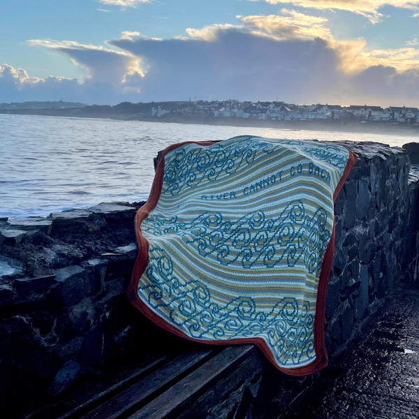 Photo of a crocheted blanket on the sea coast laid on a cliff